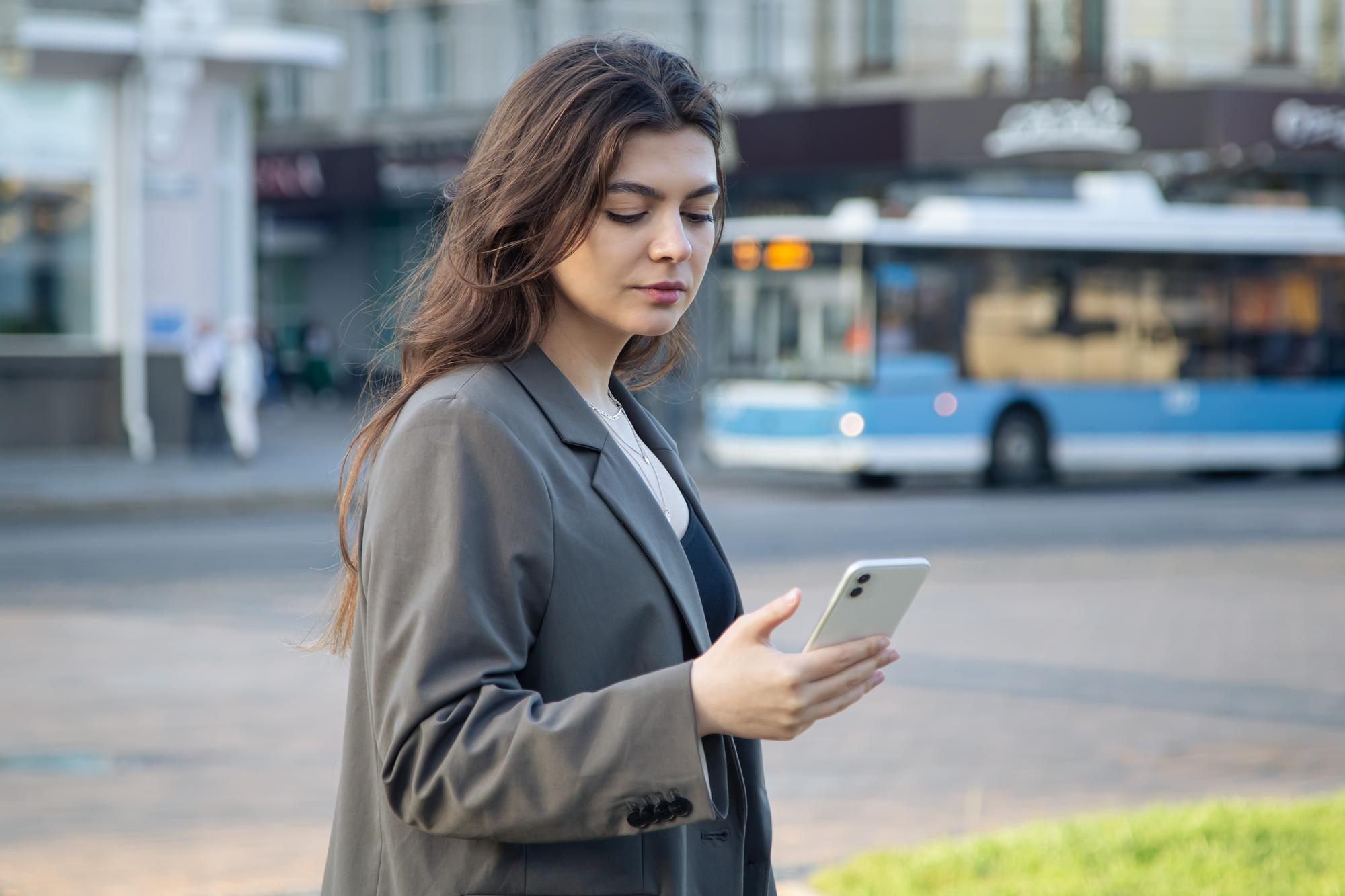 business young woman with smartphone blurred background city